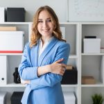 Beautiful young girl stands near a rack in the office.