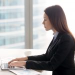 Successful serious business lady working at office desk using la